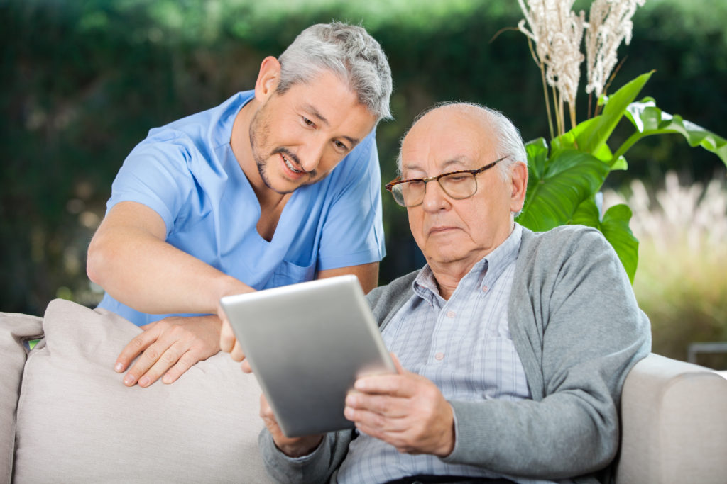 Caretaker with an elderly senior patient looking at an ipad