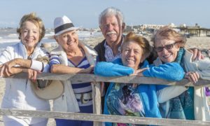 elderly friends smile on the beach as they remember their recent purchase of a safe step walk in tub